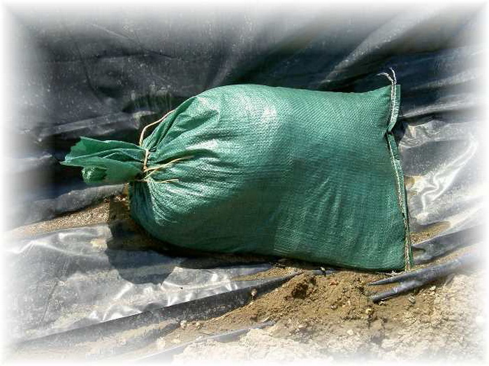 green sandbag on black plastic tarp